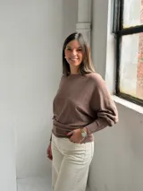 Sweater de punto color marrón, con cuello redondo, mangas largas con puños ajustados y diseño con textura acanalada vertical en el frente.