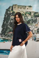 Remera de algodón color azul marino, corte relajado con hombro caído. Presenta cuello redondo blanco y bordado a mano en contraste en los puños de las mangas. Tiene un parche bordado en la parte inferior del frente.