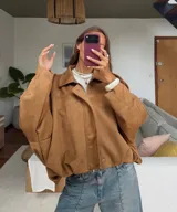 Campera tipo bomber oversized con efecto gamuza, cuello clásico, cierre frontal oculto y hombros estructurados.