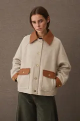 Campera de paño marrón con detalles en cuero sintético en cuello, puños y solapas de bolsillos. Presenta cierre frontal con botones dorados y dos bolsillos delanteros tipo cargo.