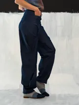 Pantalón babucha de denim azul, con corte a la cintura baja y diseño tipo origami. Presenta pliegues y costuras que favorecen la silueta. Creado y producido en Uruguay.