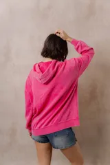 Canguro oversize fucsia con efecto washed, capucha con cordones ajustables al tono, bolsillo frontal tipo canguro y terminaciones de rib en puños y cintura.