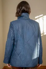 Campera tipo puffer de cuero color marrón, con diseño acolchado de rombos, cuello alto y cierre frontal metálico. Cuenta con bolsillos laterales.