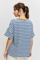 Remera de manga corta con diseño a rayas horizontales azules y blancas, cuello redondo en color tostado y parche bordado en el pecho.