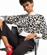 Suéter de punto con cuello alto y mangas largas, con estampado animal print de leopardo en tonos blanco, negro y marrón.