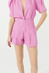 Short de lino color rosa con cintura alta, pinzas delanteras, bolsillos laterales y cierre frontal con gancho metálico.