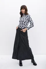 Polera de poliéster color beige con estampado geométrico en negro. Tiene cuello alto y mangas largas.