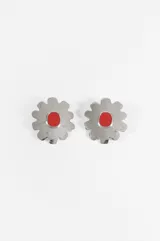 Aros caravanas con diseño de flor plateada de bordes irregulares y centro ovalado de color rojo.