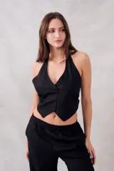 Chaleco negro con escote halter, corte al cuerpo y cierre frontal con botones.