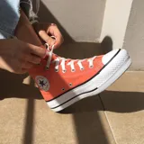 Championes Converse Chuck Taylor All Star Lift color naranja, de caña alta y plataforma blanca.