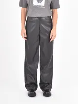 Pantalón de corte recto y tiro medio, confeccionado en cuero sintético negro, con cierre frontal y bolsillos laterales.