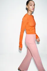 Pantalón de vestir color rosado, tiro bajo, con corte acampanado (flare) y costuras laterales marcadas. Cierre frontal con botón interior y gancho.