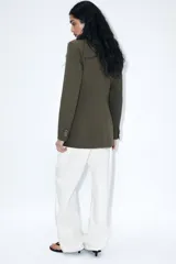 Blazer blanco de manga larga con cuello solapa y hombreras. Diseño cruzado con cierre frontal de cuatro botones y bolsillos delanteros con solapa.