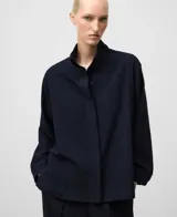 Sobrecamisa de mujer color azul marino con textura sutil de rayas verticales. Presenta un corte amplio (boxy fit), cuello mao (cuello tira) y manga larga con puño. Cierre frontal oculto por solapa.