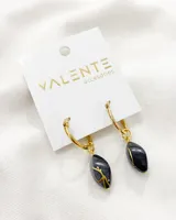 Aros colgantes con argolla dorada y dije de piedra negra con diseño dorado.