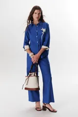 Pantalón de corte recto y amplio, confeccionado en lino color azul. Presenta cintura elastizada, cierre de cremallera y botón, ofreciendo un ajuste cómodo y fluido.