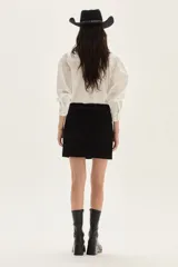 Falda corta de cuero color marrón, con diseño de flecos largos desmontables que cubren toda la prenda. Presenta un estilo western con cierre en la cintura.