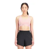 Top deportivo New Balance color rosa con espalda cruzada y logo de la marca en la banda inferior.
