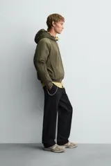 Cazadora relaxed fit color negro, confeccionada en tejido técnico ligero que repele el agua. Cuenta con cuello subido, capucha ajustable, manga larga y cierre frontal con cremallera. El interior está forrado con tejido de estructura abierta y tiene bolsillos frontales ocultos en la costura. Los acabados son elásticos.