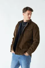 Chaqueta de pana color marrón con interior capitoneado en azul marino. Presenta cierre frontal con botones, cuello camisero y bolsillos frontales con solapa y botón.