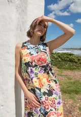 Vestido midi sin mangas con corte recto y tajos laterales en el ruedo. Presenta un estampado floral multicolor sobre base negra y cierre con botón en la espalda.