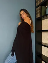 Ruana tejida a mano en punto arroz con lana merino, presenta un diseño envolvente con flecos en los extremos.