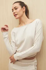 Buzo color beige de calce fluido, con cuello bote y mangas murciélago.