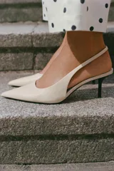 Zapato destalonado de tacón medio fino y acabado en punta, en color crudo, con tira trasera elástica.