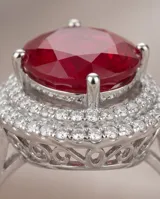 Anillo de plata 925 con piedra central ovalada de raíz de rubí en color rojo intenso, rodeada por un engaste de circonias brillantes.