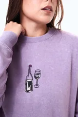 Buzo de felpa oversize color violeta con cuello redondo y estampa frontal pequeña de una botella y una copa de vino.