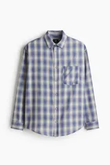 Camisa de manga larga con ajuste relajado, cuello inglés y un bolsillo aplicado en el pecho. Presenta cierre frontal de botones y bajo redondeado.