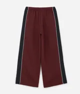 Pantalón de jogging color bordó con paneles laterales en negro y detalles de líneas blancas. Presenta un corte holgado y cintura elástica con cordón de ajuste.