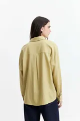 Camisa oversize color crema con detalles de puntilla roja en el frente.