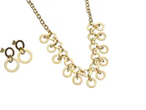 Set de collar y aros dorados con eslabones y dijes circulares calados.