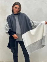 Pashmina de lana con diseño de bloques de color en gris oscuro, gris claro, blanco y negro. Presenta costuras decorativas en contraste.