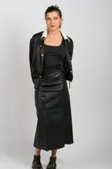 Falda larga de cuero ovino negro, de corte ligeramente acampanado, con costuras verticales visibles.