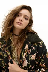 Chaqueta de denim con estampado floral vintage, corte oversized, cuello y forro interior de corderito en color verde oscuro. Cuenta con cinco bolsillos delanteros y cierre de botones metálicos ocultos.