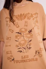 Remera color arena con estampa frontal de flores y texto "Les Tourness Bisou". Corte oversize.