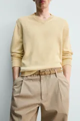Sweater de punto en mezcla de algodón, color beige, con cuello en V y mangas largas. Presenta terminaciones en rib en cuello, puños y ruedo.