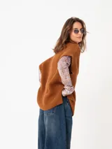 Chaleco tipo poncho de tejido de punto color tostado, con cuello polera y diseño holgado con laterales abiertos.