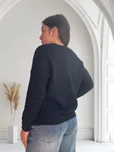 Saco de lana negro con textura de punto, escote en V y cierre frontal con botones.