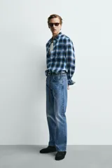 Camisa de corte regular fit confeccionada en tejido fluido de algodón y viscosa. Presenta un diseño de cuadros, cuello solapa, manga larga con puños abotonados, bolsillo en el pecho y cierre frontal con botones.