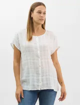 Blusa de corte fluido confeccionada en algodón con tejido texturizado de patrón a cuadros. Presenta mangas cortas caídas, escote redondo y cierre frontal con botones.