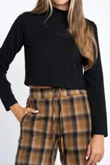 Remera de manga larga tipo polera en color negro, confeccionada en tejido de algodón y elastano. Posee un calce ajustado al cuerpo y un largo tipo crop.