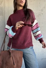 Sweater de tejido de punto con cuello redondo, cuerpo en color bordeaux y mangas con diseño de rayas horizontales en tonos bordeaux, blanco, rosado y celeste.