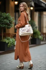 Vestido camisero midi de color marrón terracota, de manga larga, cuello solapa y cierre frontal con botones. Presenta un diseño estampado de estilo artístico abstracto en la parte frontal.