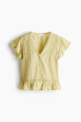 Blusa color amarillo claro en tejido liviano con alforzas e inserciones de encaje. Modelo con escote en V pronunciado, cierre frontal de botones, mangas cortas tipo mariposa y ribete con volados en el ruedo.