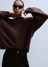 Jersey de punto marrón con cuello redondo, manga larga caída y diseño holgado.