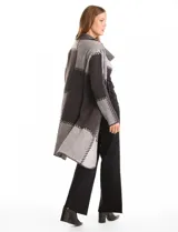 Cardigan largo tejido con diseño patchwork en tonos grises y negros. Presenta cuello con amplia solapa, diseño abierto sin botones y bolsillos delanteros amplios.