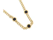 Collar de acero con baño de oro y cadena de eslabones gruesos. Contiene tres dijes circulares con ónix negro y bordes con números romanos.